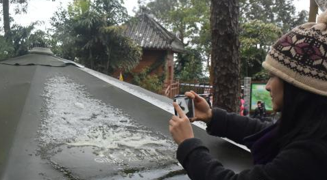 攝影愛(ài)好者爬上高處拍攝遮陽(yáng)傘上的積雪