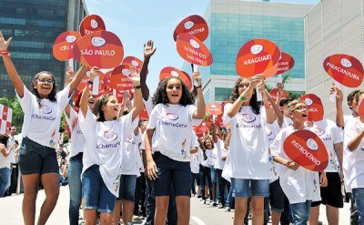 巴西小學(xué)生在儀式上手舉印有火炬?zhèn)鬟f城市名稱的牌子