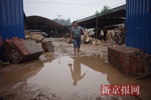 7月23日，橋東板廠門口，梓陽爸爸張?zhí)K輝從災(zāi)后工廠里走出來。新京報記者 王嘉寧 攝