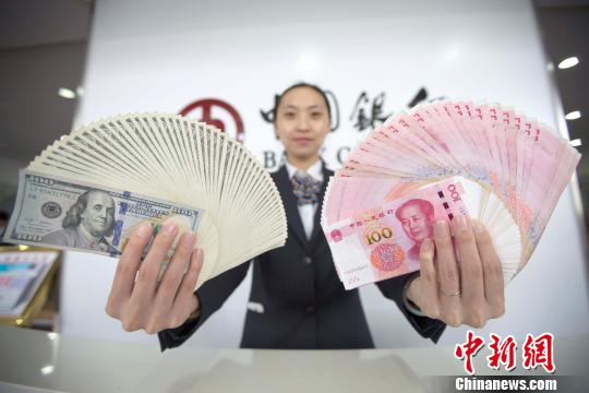 山西太原，銀行工作人員展示人民幣、美元。張?jiān)?攝