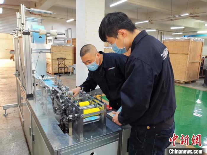 資料圖：技術(shù)工人在對口罩機生產(chǎn)線進行最后調(diào)試。姜輝 攝